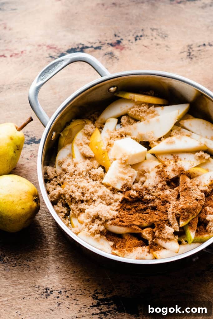 A pan with pear slices, brown sugar, spices, and butter on a wooden surface