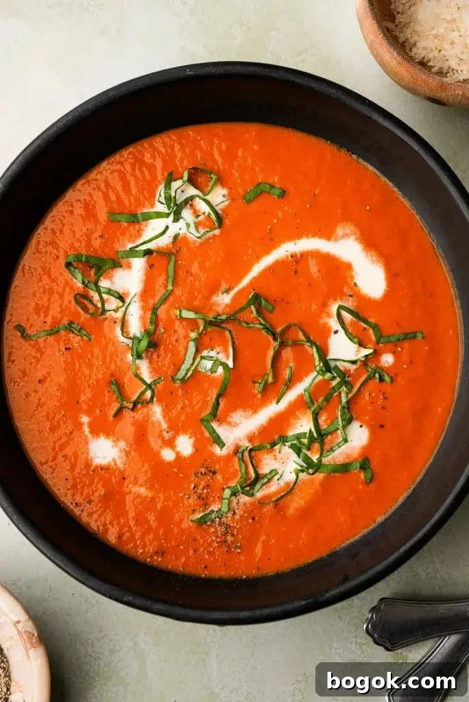 overhead shot of tomato bisque soup with basil, cream, and pepper