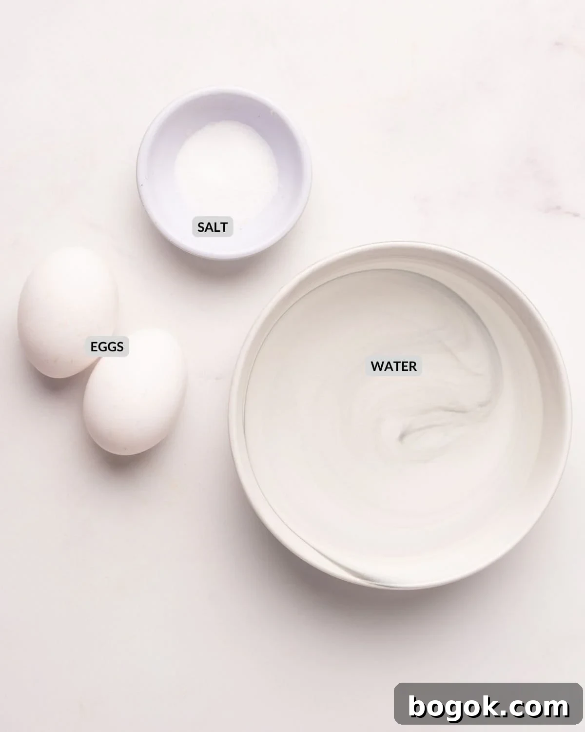 Microwave Method for Perfect Hard-Boiled Eggs in Minutes 3 An overhead image of two eggs, salt in a small bowl, and water in another bowl.