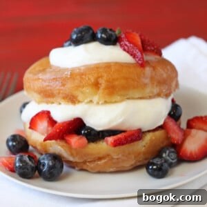 Donut Trifle Dessert: Layered Mini Trifles with Glazed Donuts 2 Close up of a Doughnut Strawberry Shortcake topped with fruit on a white plate.