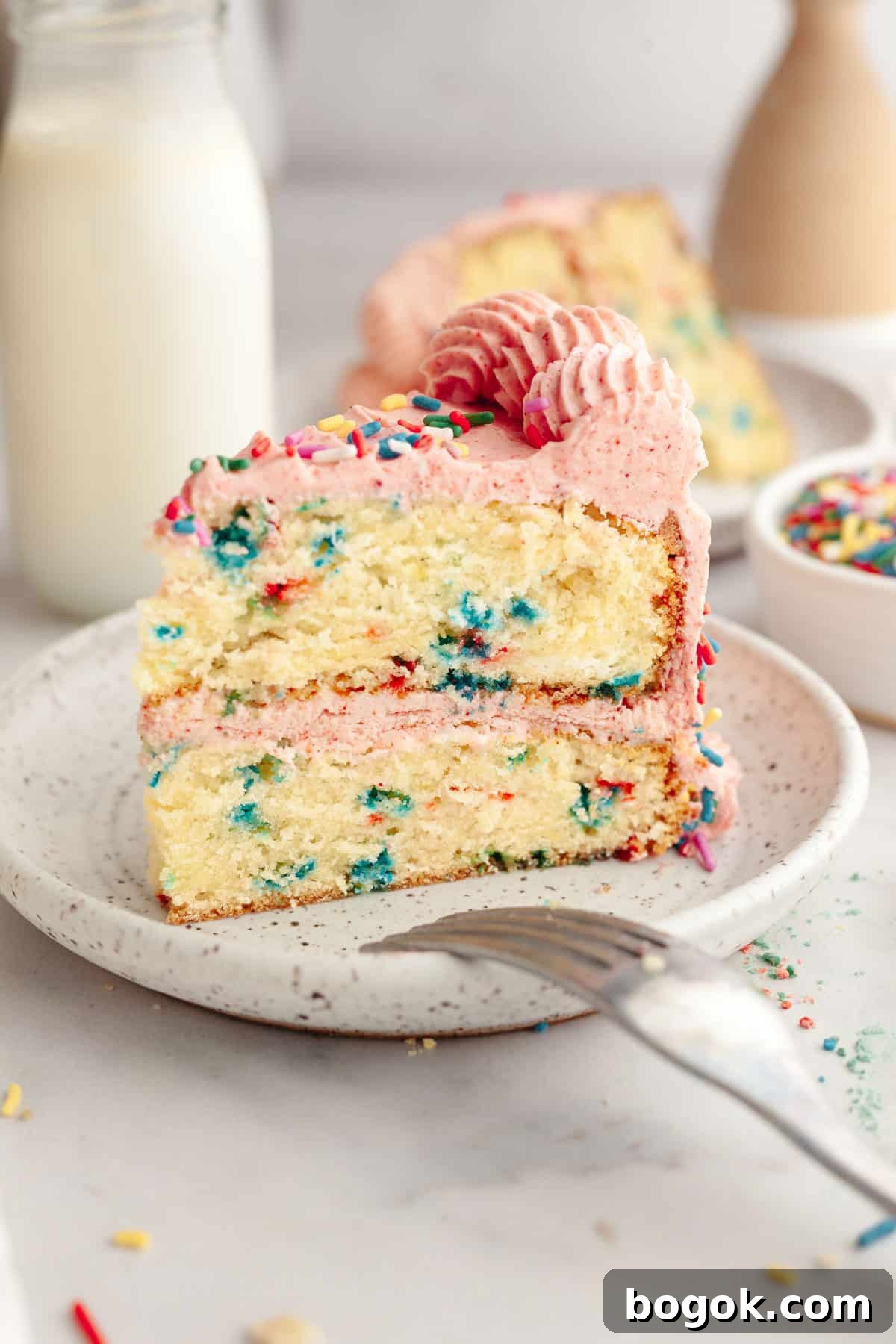A slice of strawberry funfetti cake on a small plate.