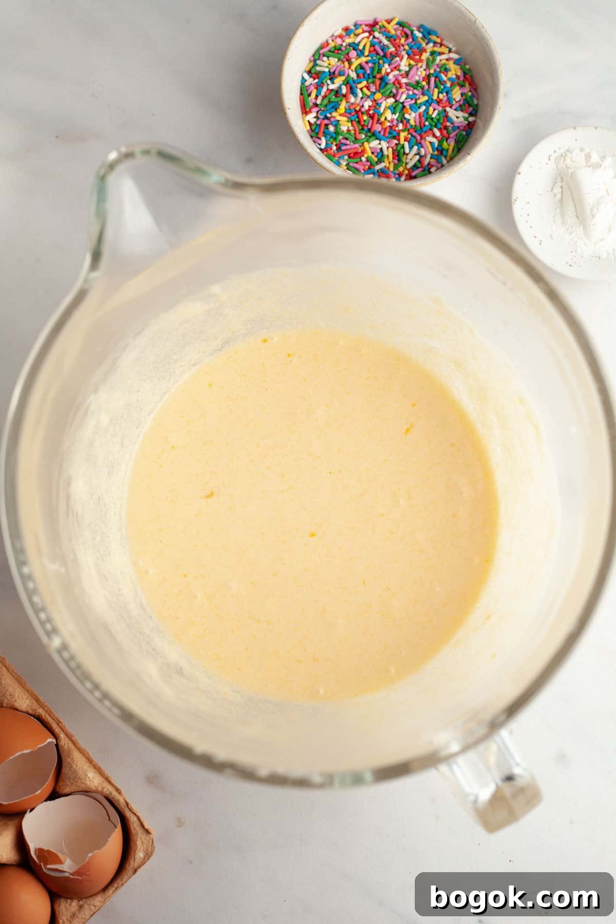 A large glass mixing bowl with cake batter in it.