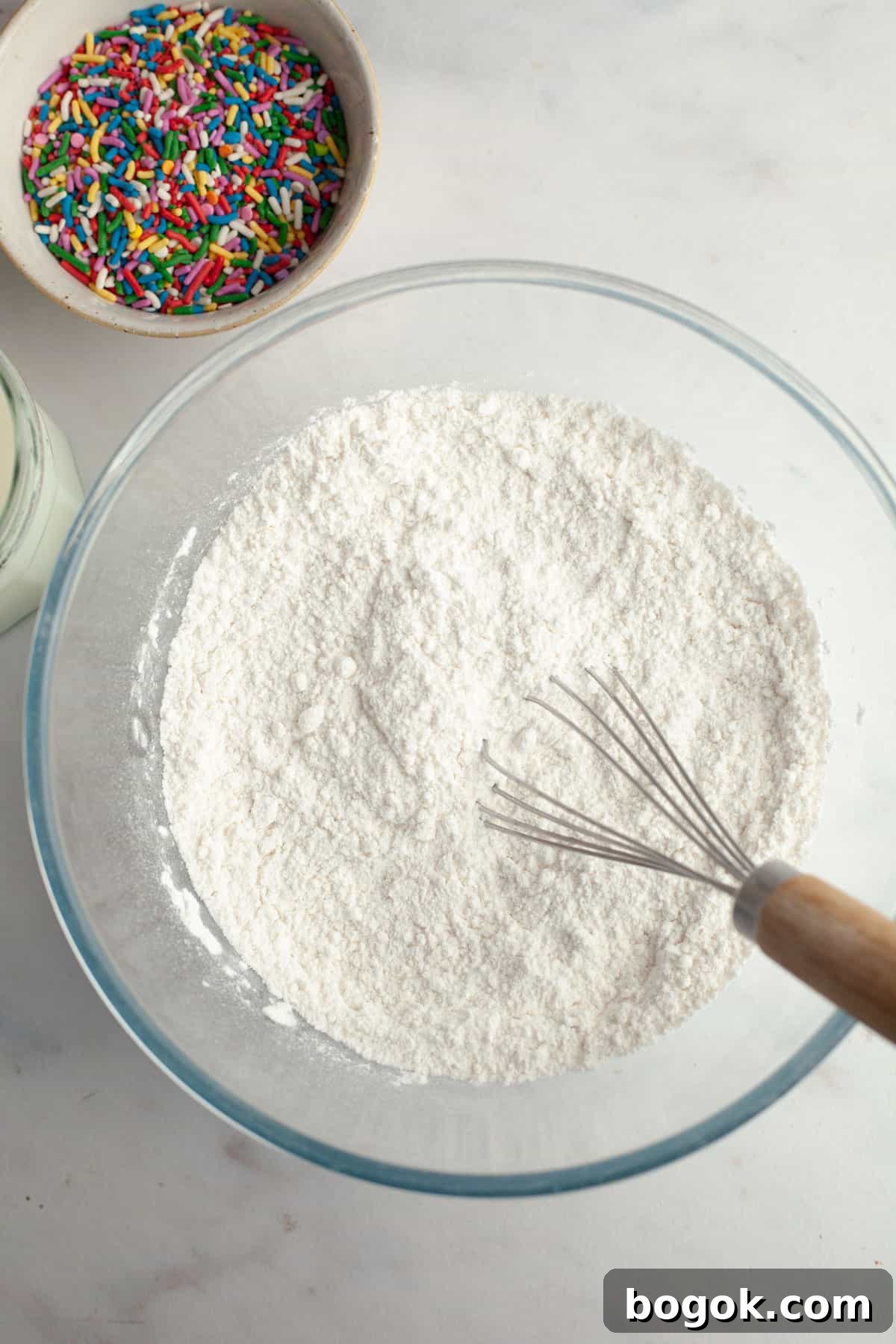 A bowl with flour and a whisk.