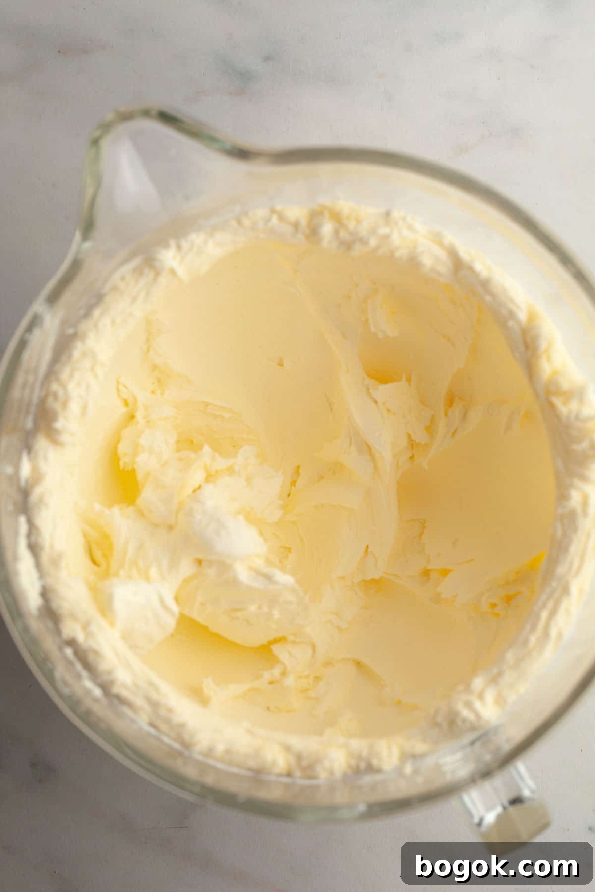 A large glass bowl with white frosting in it.