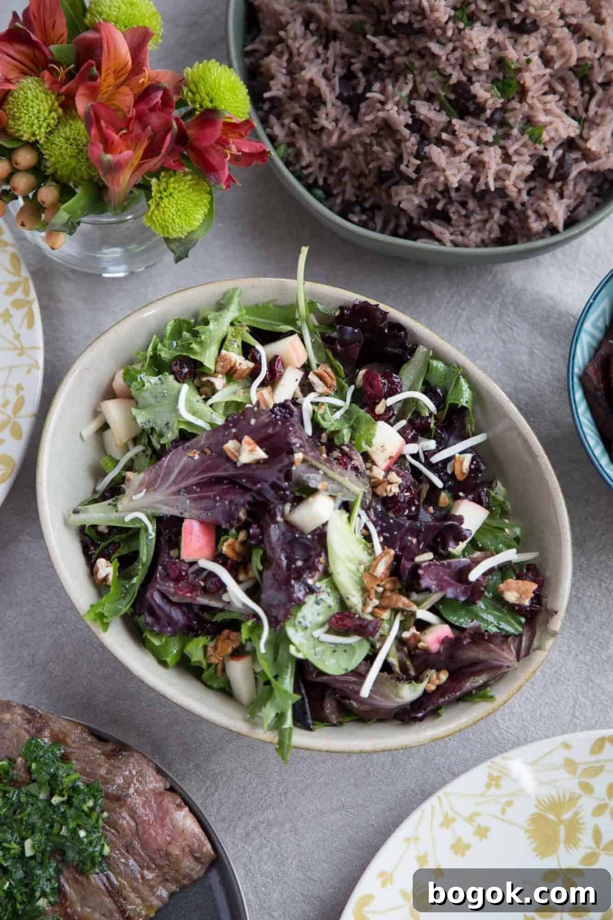 cream bowl filled with winter fruit salad on a table with rice and steak.