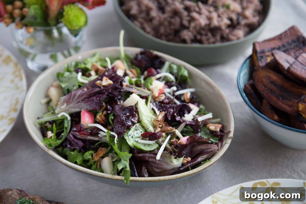 winter fruit salad in a cream bowl next to a bowl of rice and a platter of steak.