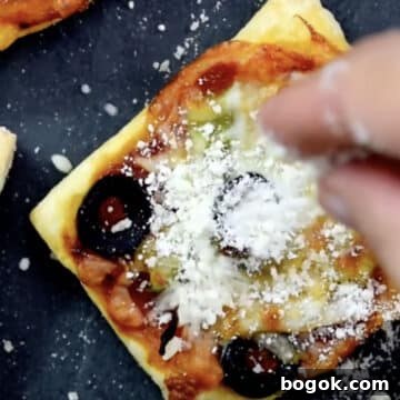 Parmesan cheese being sprinkled on top of mini appetizer.