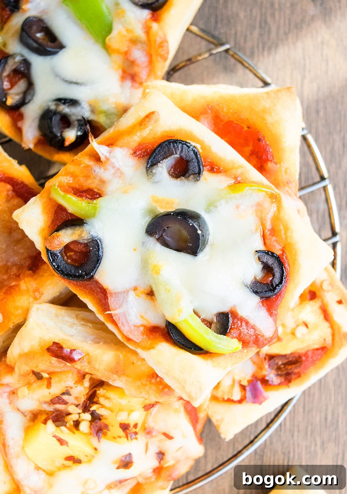 Puff with veggies, olives and melted cheese on cooling rack.