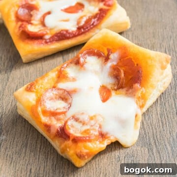 Easy mini puff pastry pizza with mini pepperoni and melted cheese on wood background.