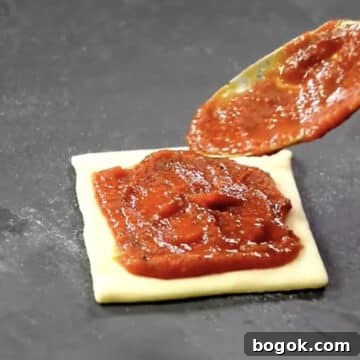 Pizza sauce being spread on top of dough.