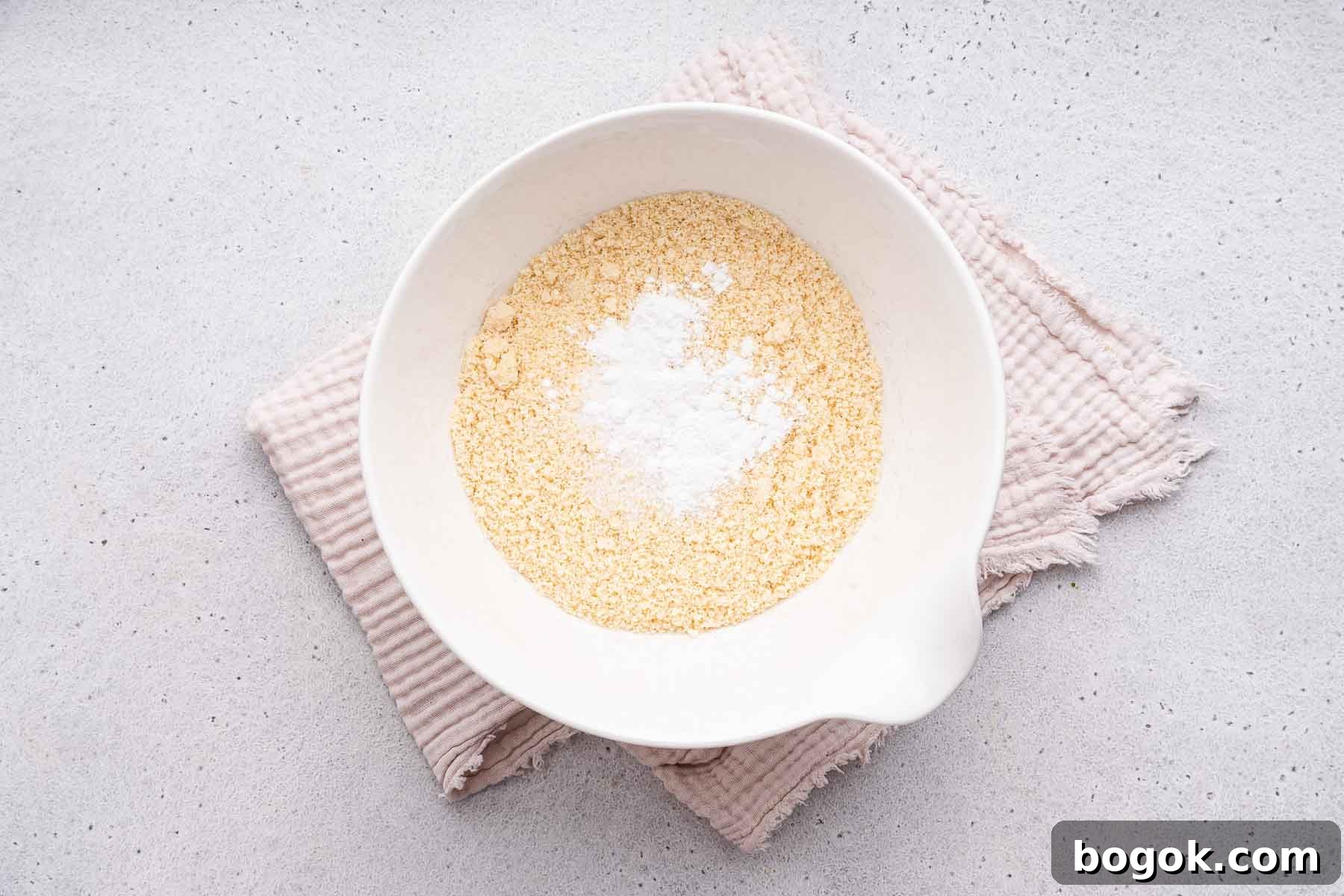 Dry ingredients in a white mixing bowl over a towel.