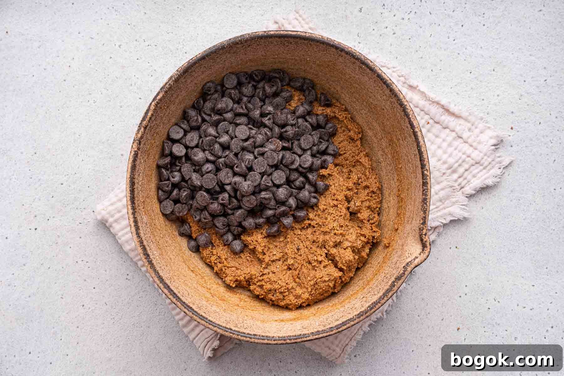 Adding chocolate chips to a bowl of brown dough.