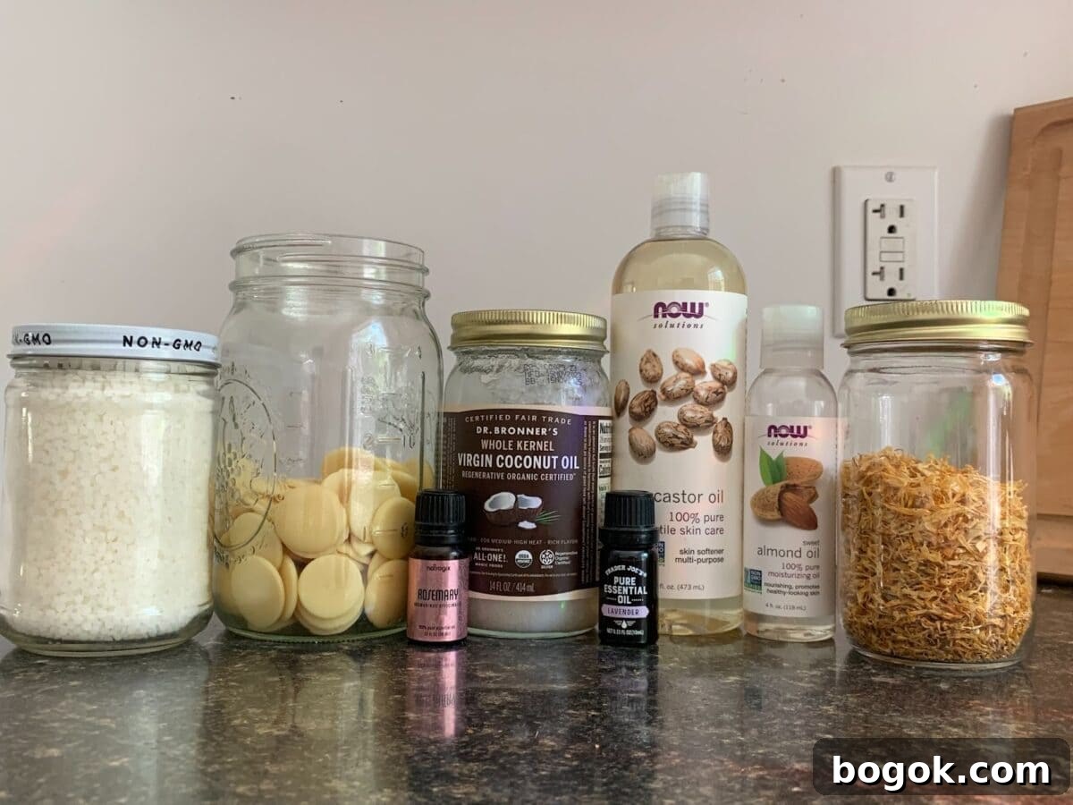 A countertop is shown with an array of jars and bottles containing ingredients such as castor oil, almond oil, coconut oil, cocoa butter wafers, and what appears to be calendula.