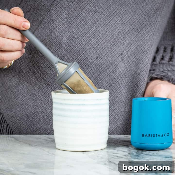 womans hands placing a brew it stick coffee maker into a handmade mug on a marble surface