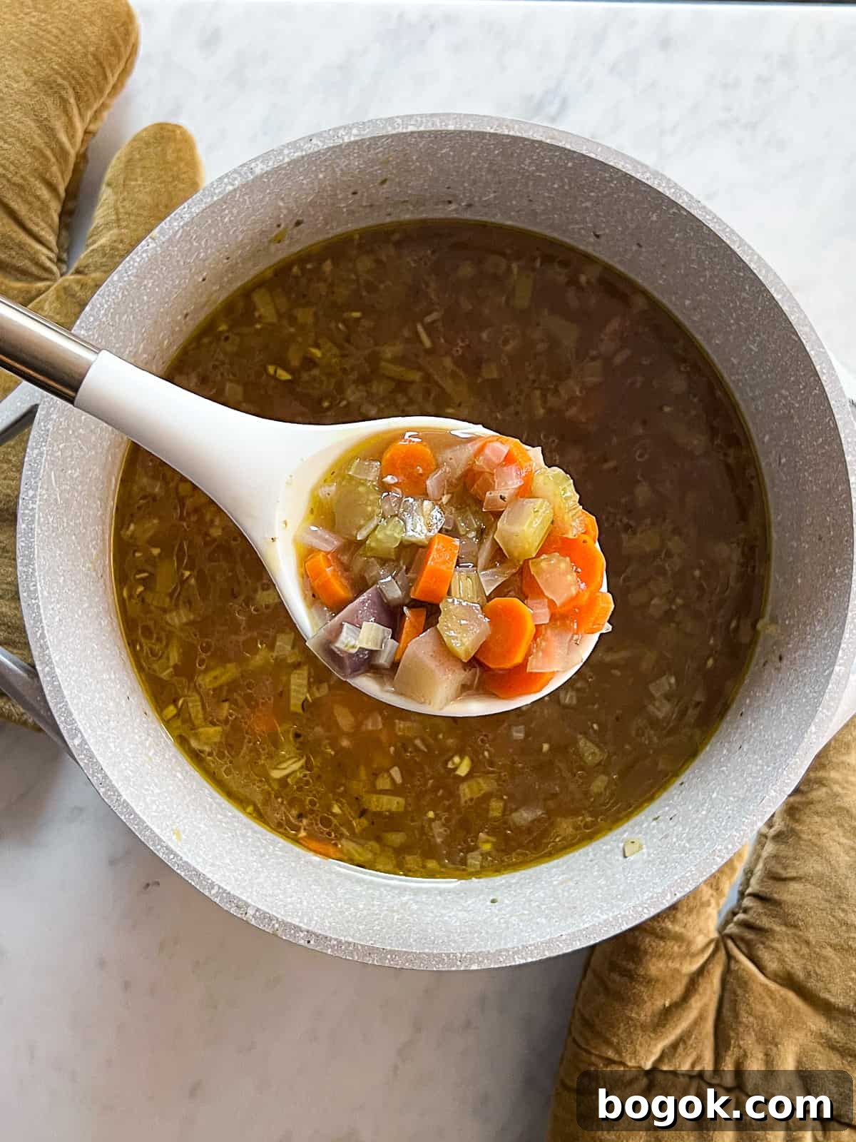 Closeup of ladle over a soup pot filled with homemade Vegetable Soup With Potatoes