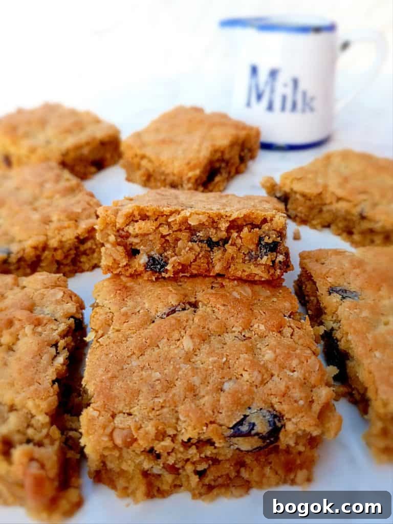 Amish Oatmeal Chocolate Chip Bars Recipe — Chewy, Old-Fashioned Treat 5 Amish oat bars with raisins instead of chocolate chips, and a small milk pitcher on the side.