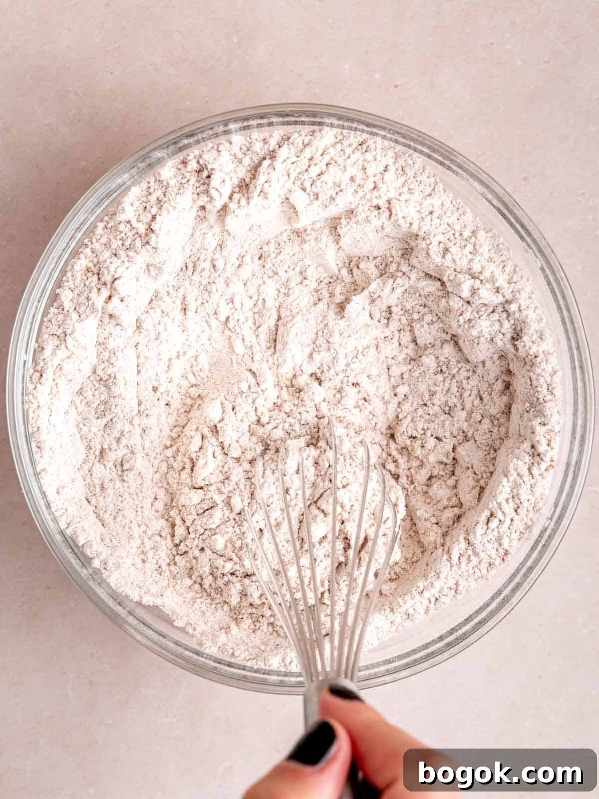 Whisking together flour, baking powder, baking soda, cinnamon, and pumpkin pie spice.