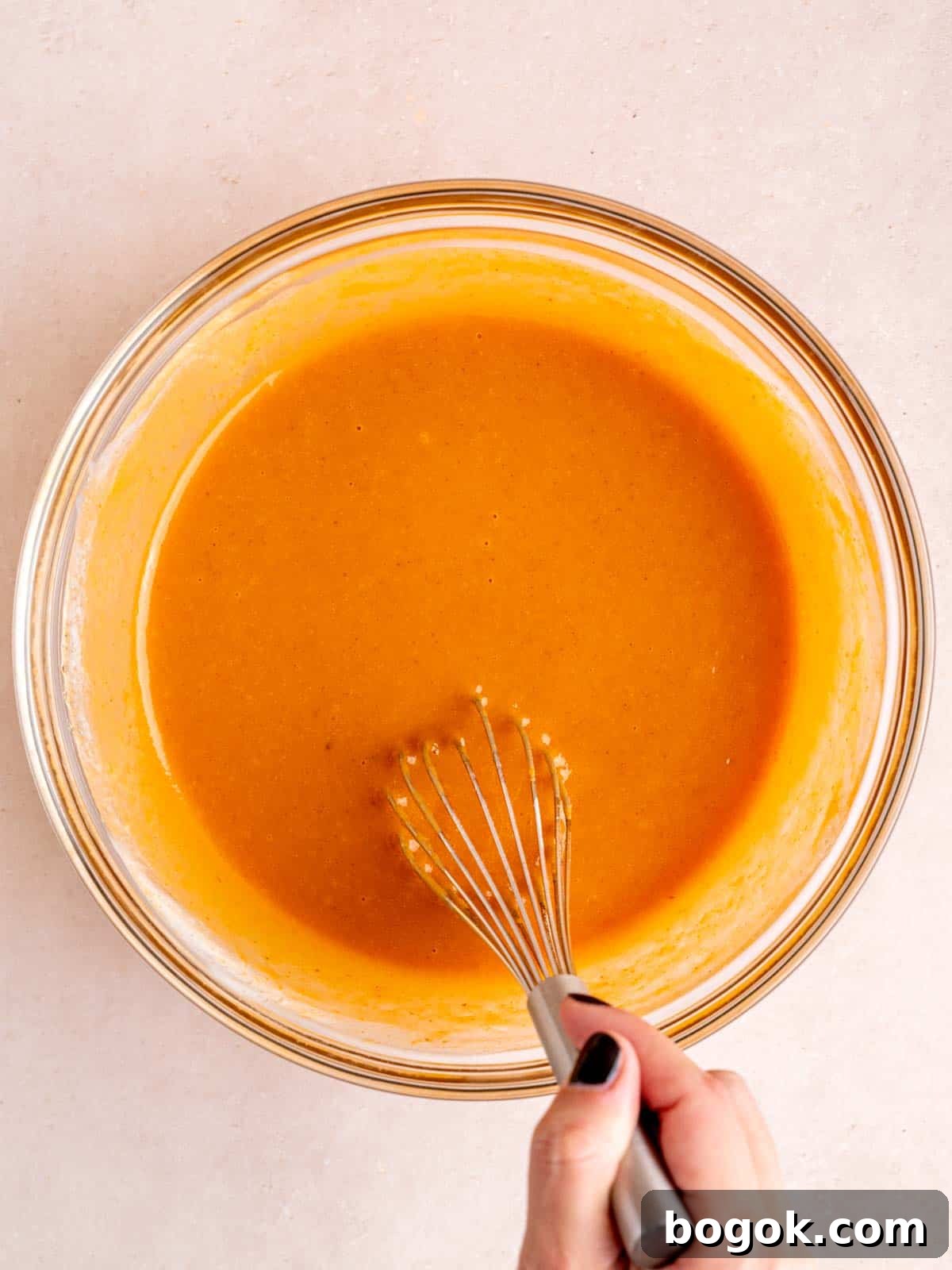 Whisking vegetable oil, granulated and brown sugar, eggs, vanilla extract, kefir, and pumpkin puree in a bowl.