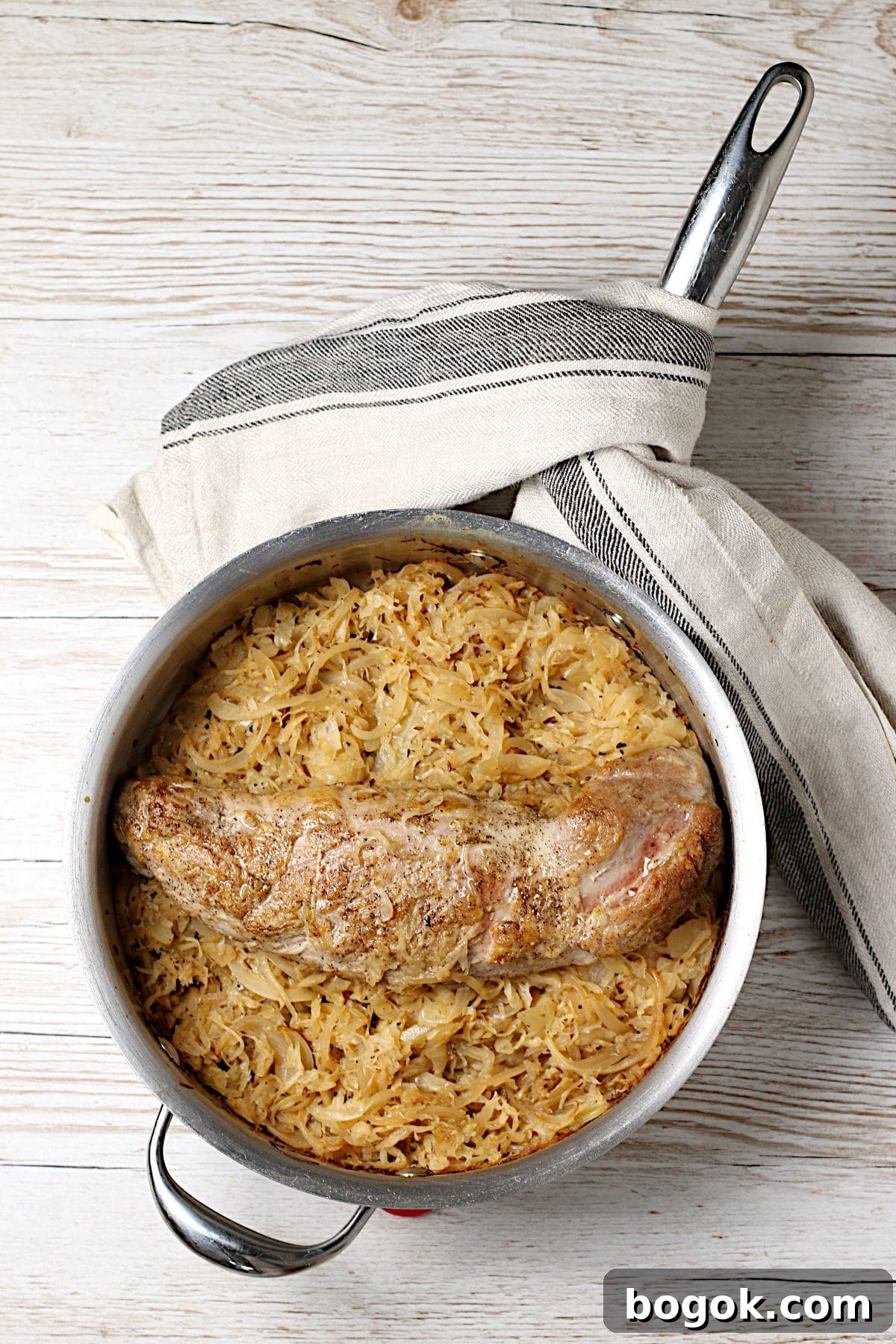 Crispy Roasted Pork Tenderloin with Tangy Sauerkraut 2 Whole pork tenderloin on a bed of sauerkraut in a saute pan.