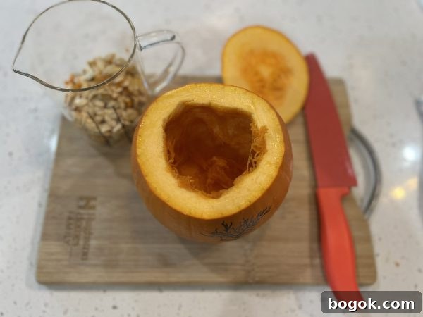 Homemade Pumpkin Puree a pumpkin with the top cut off and the seeds and guts taken out and put into a glass measuring cup sitting on a wooden cutting board.