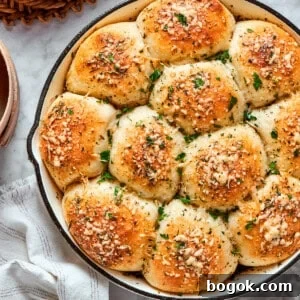A skillet of baked pizza bites next to a bowl of sauce.