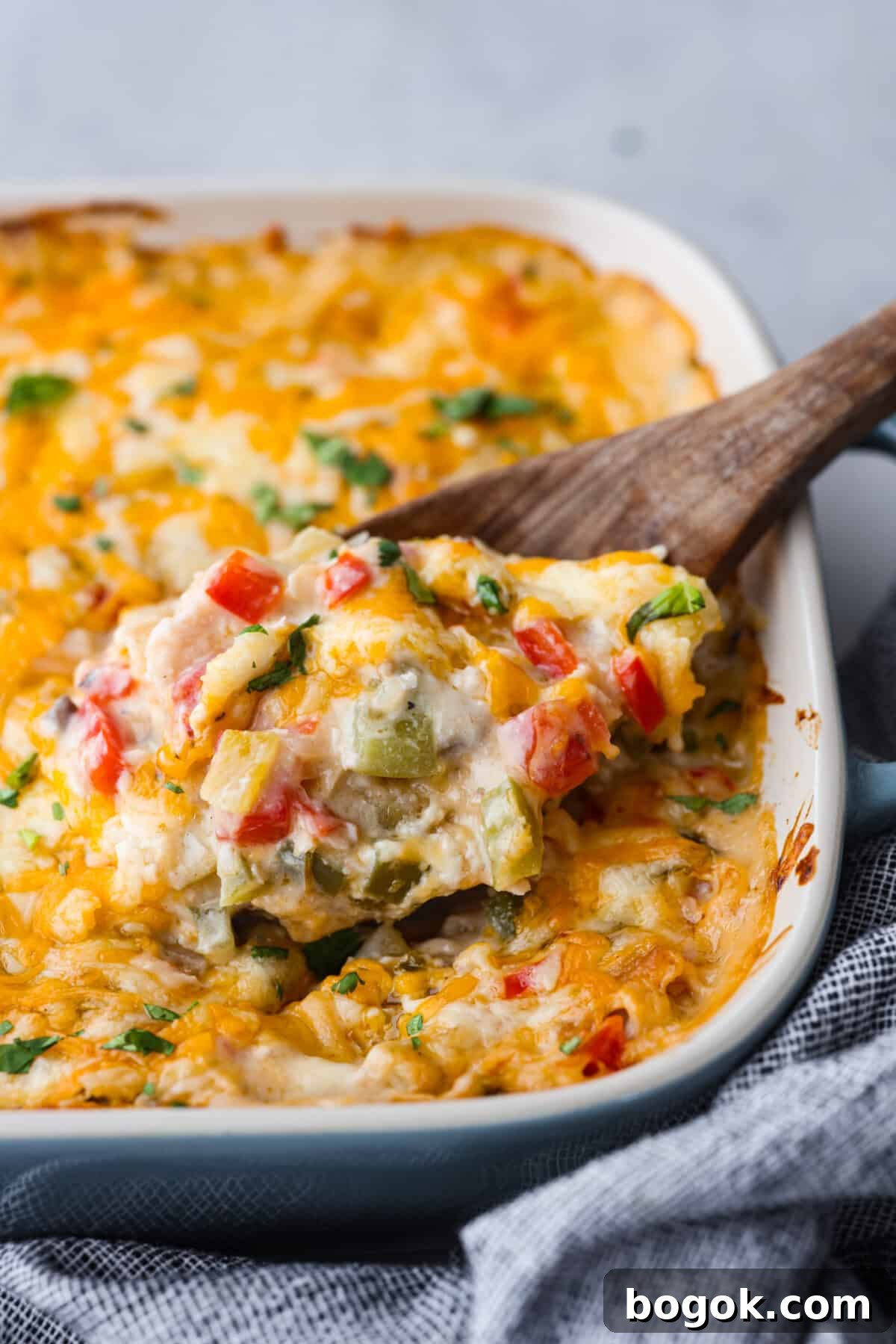Close view of king ranch casserole in a baking dish with a wooden serving spoon.