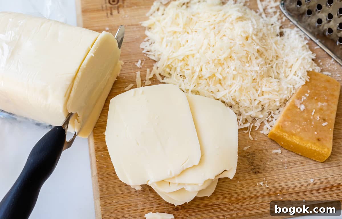 Ultimate Homemade Lasagna Recipe for Savory, Cheesy Layers 8 block of mozzarella cheese being sliced with a knife, shredded parmesan in the background.