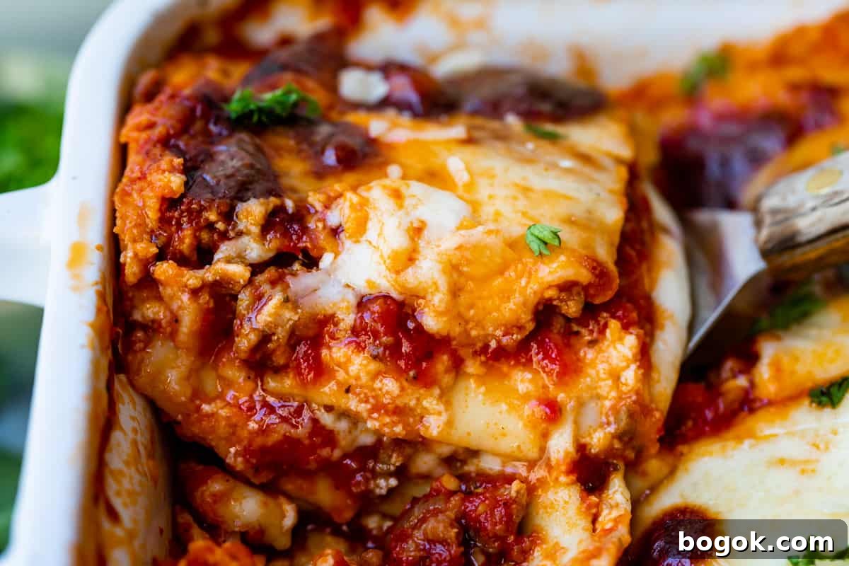 Ultimate Homemade Lasagna Recipe for Savory, Cheesy Layers 11 a slice of lasagna being lifted from a white pan.