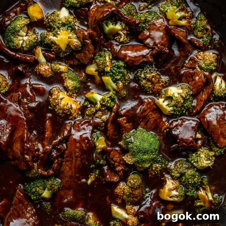 Close-up of beef and broccoli stir-fry in a dark sauce inside a skillet.