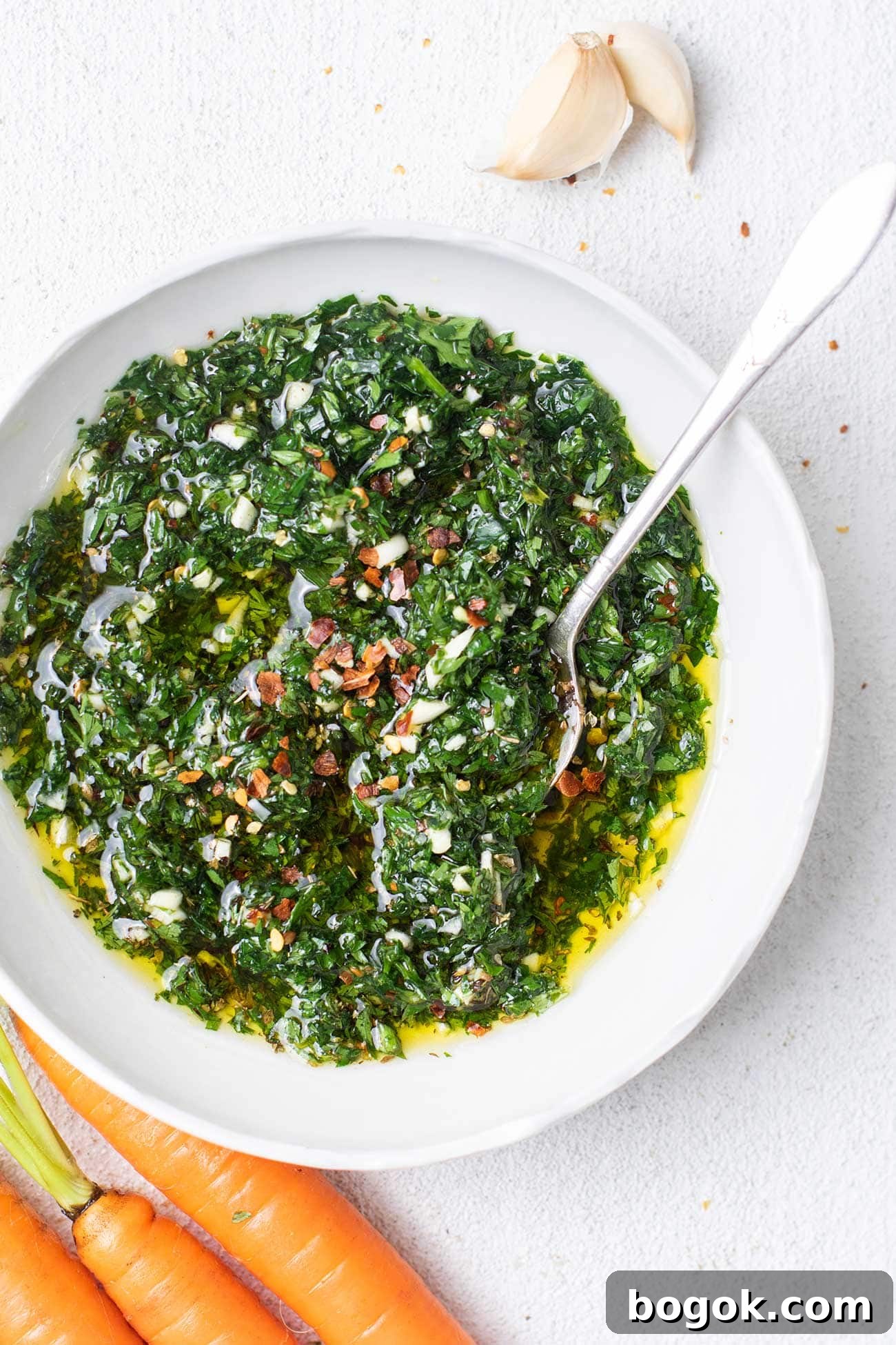 A close up look at a bowl of carrot top chimichurri garnished with red pepper flakes.