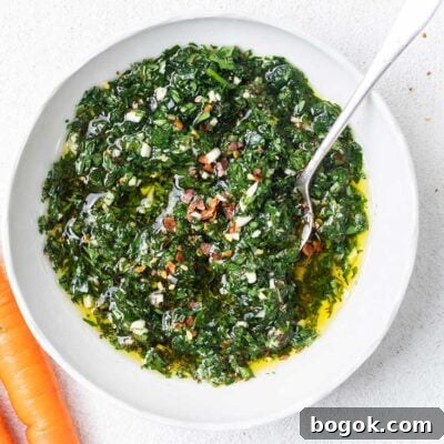 A vibrant green carrot top chimichurri recipe shown in a white bowl.