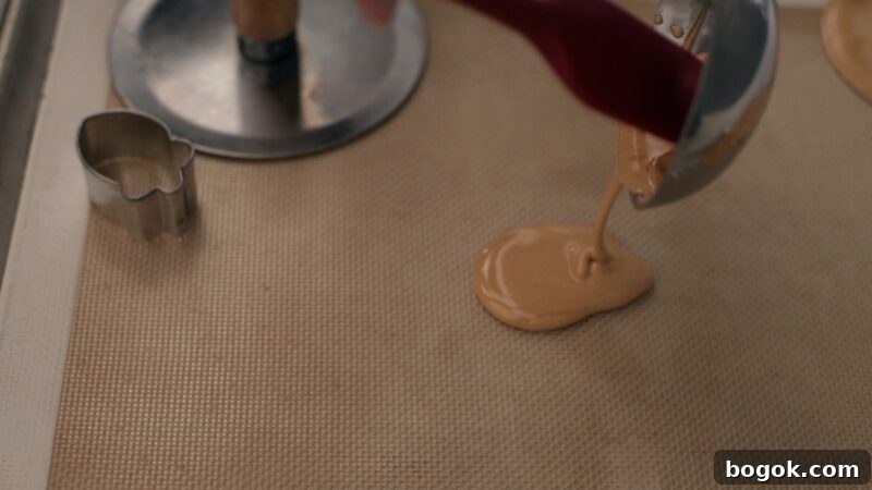 5-Minute Dalgona Candy Recipe: Quick Korean Honeycomb Toffee 12 A spatula is scrapping the melted dalgona candy from the ladle and poured on a silicon mat.