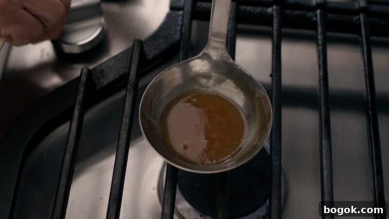 5-Minute Dalgona Candy Recipe: Quick Korean Honeycomb Toffee 9 Sugar has caramelized to amber color in a ladle over stove.