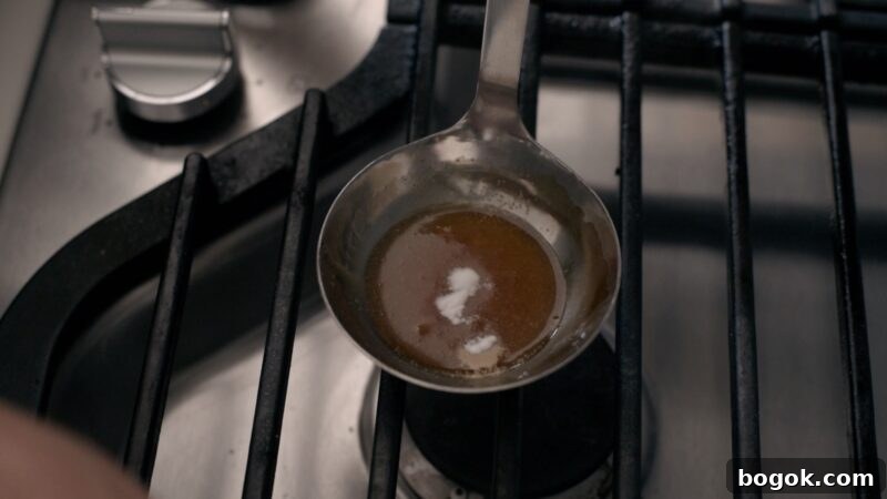 5-Minute Dalgona Candy Recipe: Quick Korean Honeycomb Toffee 10 A small amount of baking soda is added to the caramelized sugar in a ladle.