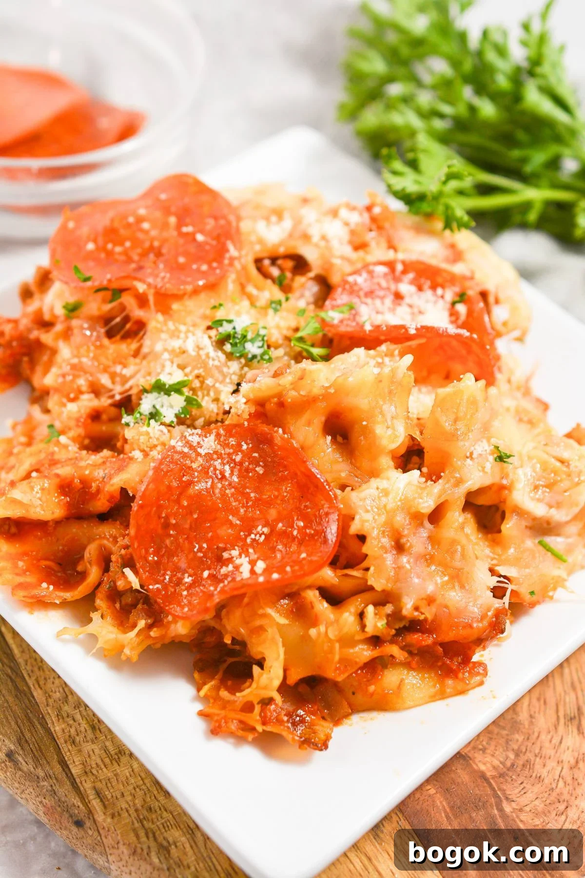Slow-Cooker Pizza Casserole Recipe for Busy Weeknights 2 A white plate with a portion of pizza pasta casserole, garnished with parsley.