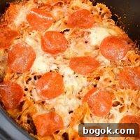 A close up of a slow cooker filled with pizza casserole, topped with pepperoni.
