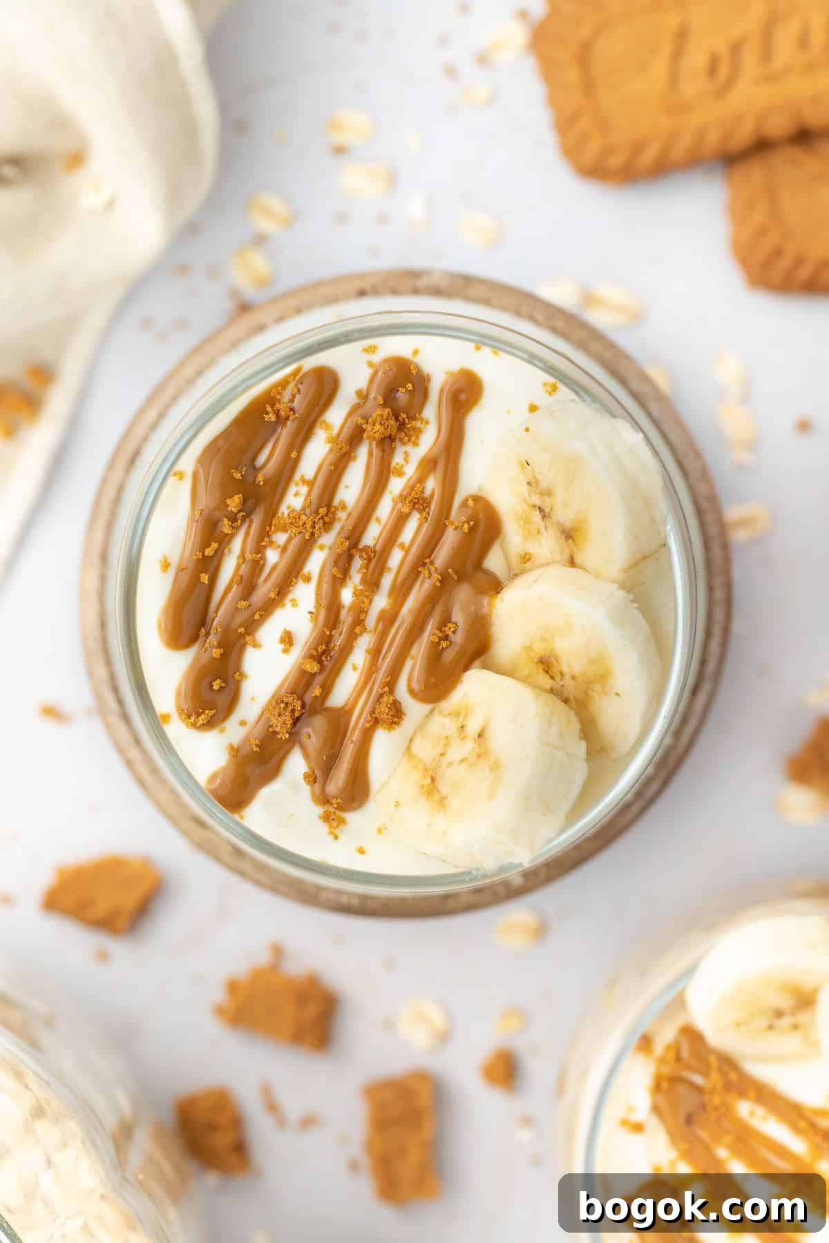 Creamy Biscoff Overnight Oats Recipe for Quick Breakfast 7 Overhead shot of overnight oats in a glass jar topped with yoghurt, slices of banana and a drizzle of Biscoff spread.