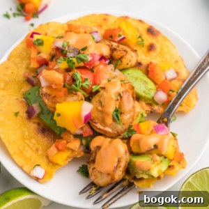 Mango Salsa Grilled Shrimp Tostadas with Chipotle Cream 6 A fork is placed on a white plate with a shrimp tostada.