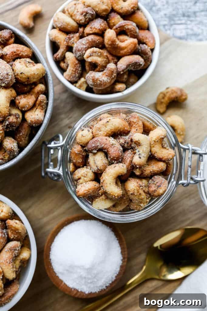 small bowls of air fryer salt and pepper roasted cashews on a round wooden cutting board