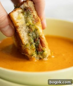dunking grilled cheese into soup in green bowl