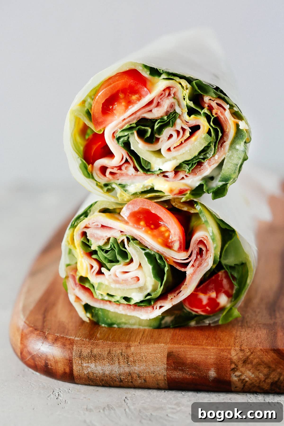 A lettuce wrap sandwich sitting on top of a wooden cutting board