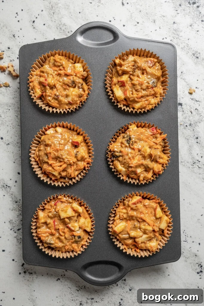 This jumbo morning glory muffins recipe with fruity and nutty add-ins is packed with warm spices for the perfect breakfast bite. Pouring the batter into the liners.