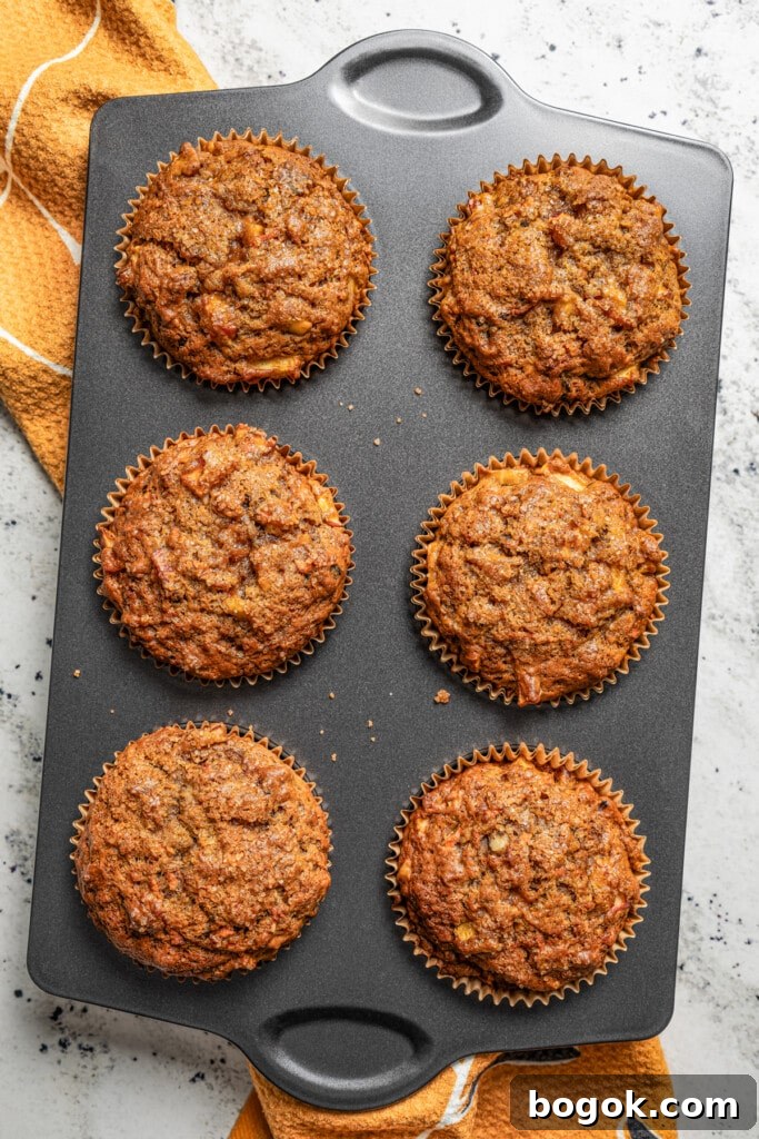 This jumbo morning glory muffins recipe with fruity and nutty add-ins is packed with warm spices for the perfect breakfast bite. Photo of six muffins in a muffin pan.
