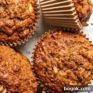 Moist Morning Glory Muffins with Carrots, Apples & Coconut 3 Photo of five morning glory muffins set on a light-colored surface.