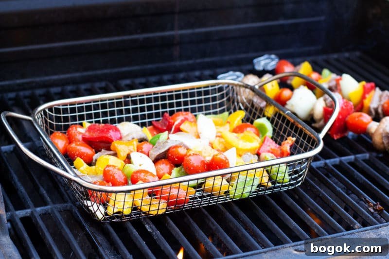 Chopped steak and vegetables in a grilling basket on the grill.