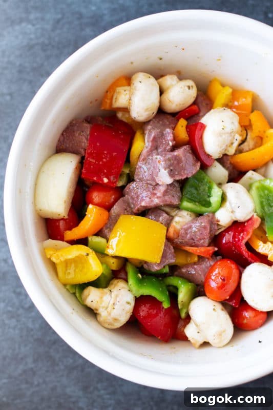 Bowl containing steak and vegetables marinated in Italian seasoning.