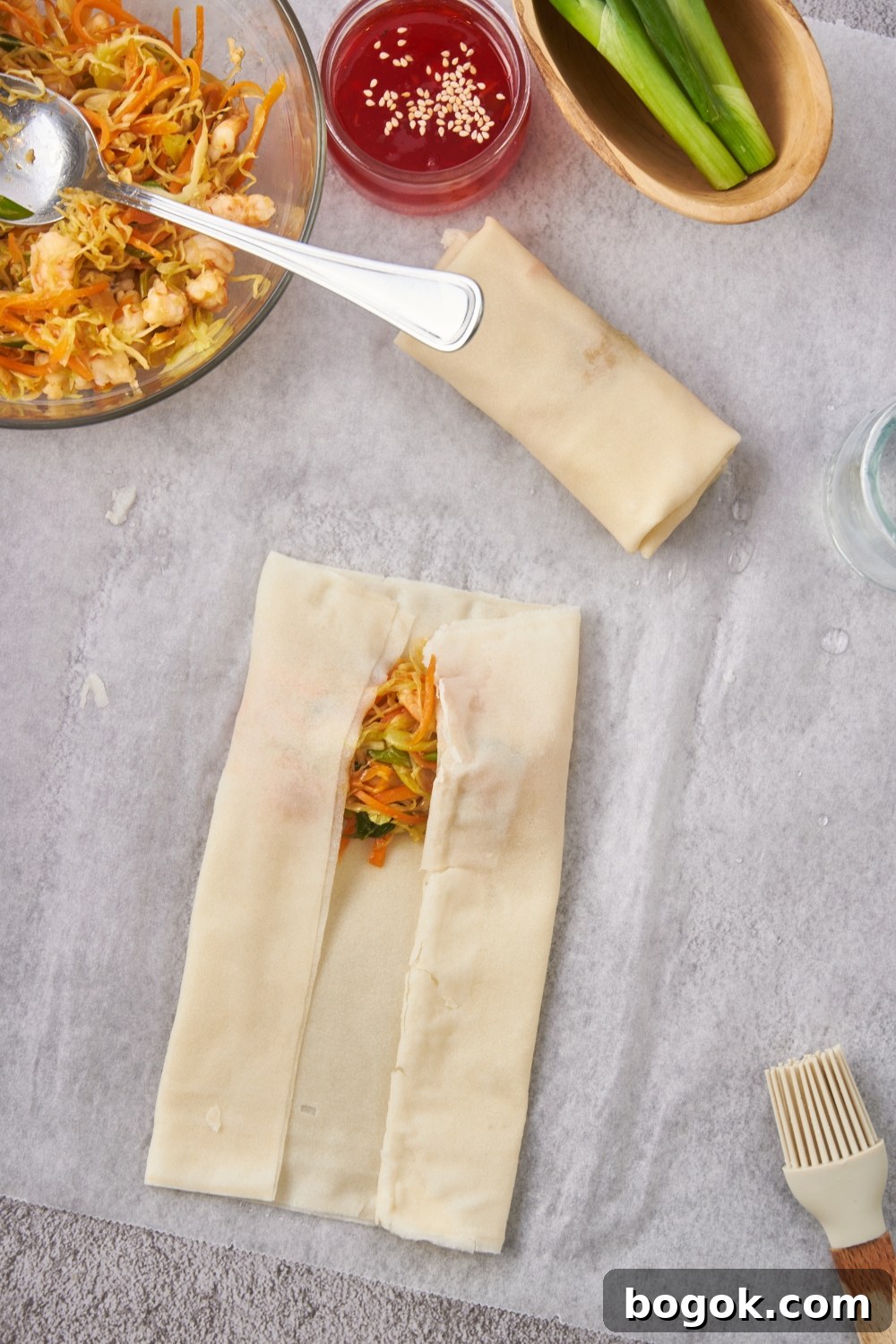 Diced veggies and shrimp being wrapped in an egg roll wrapper.