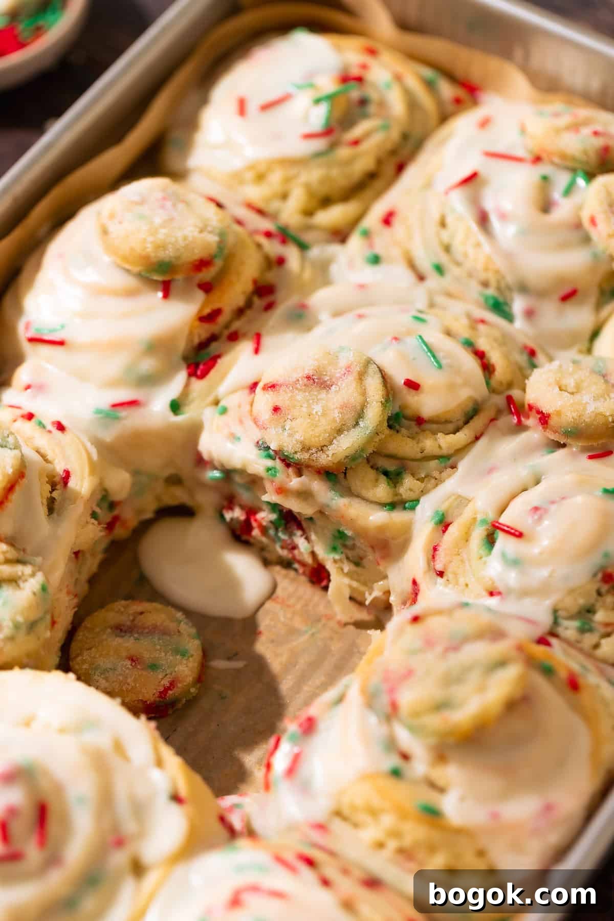 Christmas sugar cookie rolls covered in creamy vanilla icing and holiday sprinkles.