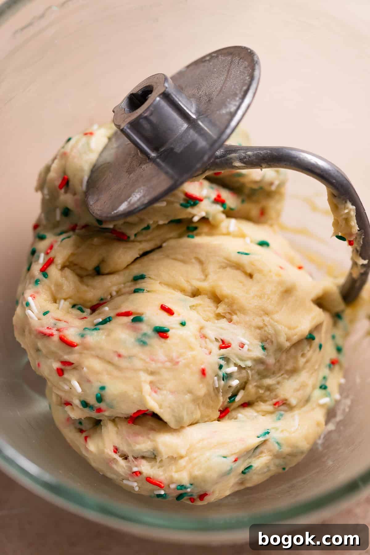 Sweet roll dough kneaded with green and red sprinkles in a mixer bowl.