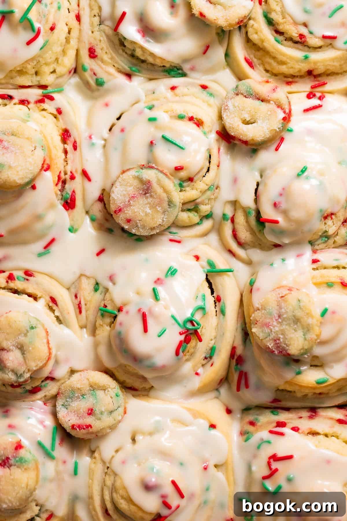 Christmas sugar cookie rolls covered in creamy vanilla icing and holiday sprinkles.